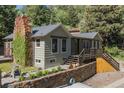 Home featuring a stone chimney, wooden deck and steps, surrounded by greenery at 55 Two Moon Rd, Idaho Springs, CO 80452