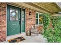Welcoming front entrance with a decorative green door, brick facade and charming decorative touches at 6880 E Appleton Cir, Centennial, CO 80112