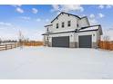 Two-story house with gray siding and a two-car garage in a snowy landscape at 4487 Boone Cir, Brighton, CO 80601