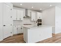 Modern kitchen with white cabinets, stainless steel appliances, and a large island at 3361 N Buchanan Way, Aurora, CO 80019