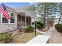 Charming exterior of a home with well-maintained landscaping, a covered front porch, and a traditional American flag at 9954 W Progress Pl, Littleton, CO 80123