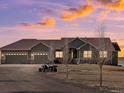 Stunning exterior view of a home with a three-car garage at dusk with a beautiful colorful sunset sky at 14077 Indianfield Ct, Hudson, CO 80642