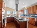 Gourmet kitchen featuring granite countertops, stainless steel appliances, and a large island with cooktop and sink at 14077 Indianfield Ct, Hudson, CO 80642