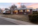 Charming single-story brick home featuring solar panels, a cozy porch swing, and a well-maintained lawn at 6903 W 52Nd Pl, Arvada, CO 80002