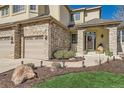Close-up of the home's entry, showcasing a stone archway, manicured landscaping, and a three-car garage at 10337 Carriage Club Dr, Lone Tree, CO 80124