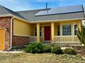 A close up view of the home's exterior featuring a red door and a cozy, white railed front porch at 6596 Silverleaf Ave, Firestone, CO 80504