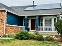 Inviting front porch with blue siding, solar panels, and manicured landscaping at 6596 Silverleaf Ave, Firestone, CO 80504