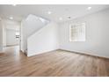 Bright living room features wood-look floors, a large window, and adjacent staircase, offering an inviting atmosphere at 24737 E 40Th Ave, Aurora, CO 80019