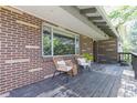 Relaxing covered porch with chairs, a small table, and a brick facade with large windows at 13990 Berry Rd, Golden, CO 80401
