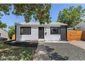 Charming home featuring white siding, black trim, and a landscaped front yard with mature trees providing shade at 1670 S Quieto Ct, Denver, CO 80223