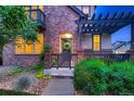 Inviting brick home featuring a charming front porch and a beautifully landscaped yard at 237 Dayton St, Denver, CO 80230