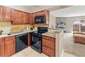 Bright kitchen featuring tile floors, dark cabinets, granite countertops, and black appliances, open to the living room at 430 Zang St # 4-103, Lakewood, CO 80228