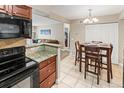 Bright kitchen featuring tile floors, dark cabinets, granite countertops, and black appliances, open to the dining area at 430 Zang St # 4-103, Lakewood, CO 80228