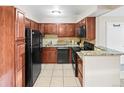 Bright kitchen featuring tile floors, dark cabinets, granite countertops, and black appliances at 430 Zang St # 4-103, Lakewood, CO 80228