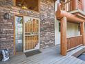 Charming entryway with stone accents, log beams, and a secure screen door offers a warm welcome at 7076 Boreas Rd, Larkspur, CO 80118