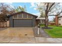 Exterior of single Gathering home with a grey brick facade, attached garage, and manicured lawn at 7719 Everett Way, Arvada, CO 80005