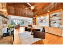 Spacious living room with wood-paneled ceilings, stone fireplace, and built-in shelving at 350 Tower Hill Cir, Golden, CO 80401