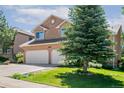 Two-story home with a two-car garage, green lawn and landscaping, with a focus on trees at 531 Saber Creek Dr, Monument, CO 80132