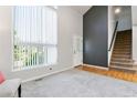Bright living room featuring high ceilings, large window, hardwood floors, and adjacent carpeted staircase at 531 Saber Creek Dr, Monument, CO 80132
