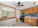 Cozy kitchen with wood cabinets, tile backsplash, and appliances, seamlessly connected to the living area at 6819 Reno Dr, Arvada, CO 80002