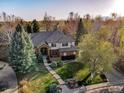 Breathtaking aerial showcasing a beautiful brick house with mature trees, blue skies, and mountain views at 2464 Ginny Way, Lafayette, CO 80026