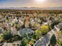 Expansive neighborhood aerial view with a grand brick home surrounded by lush trees and mountain backdrop at 2464 Ginny Way, Lafayette, CO 80026