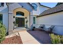 Inviting front porch with brick accents, seating area, and elegant entryway at 327 Ingleton Ct, Castle Pines, CO 80108