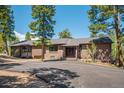 Brick home with an asphalt driveway is surrounded by mature trees and well-maintained landscaping at 7845 Armadillo Trl, Evergreen, CO 80439