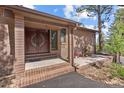 Covered front entrance with brick pillars and a decorative double door with a decorative, circular glass panel at 7845 Armadillo Trl, Evergreen, CO 80439
