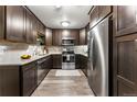 Modern kitchen featuring dark cabinetry, granite countertops, and stainless steel appliances at 665 S Alton Way # 6D, Denver, CO 80247