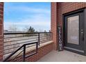 Charming covered front porch entry with a brick pillar and black railing on a sunny day at 5471 W 97Th Pl # F, Westminster, CO 80020