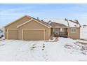 Tan house with a three-car garage and snowy yard at 7295 Sunset Ave, Elizabeth, CO 80107