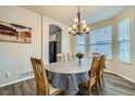 Dining room with a modern chandelier, wood floors, and a large window for natural light at 17611 E 104Th Pl, Commerce City, CO 80022