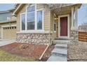 Charming front entrance showcasing stone accents, a red front door, and concrete steps at 17611 E 104Th Pl, Commerce City, CO 80022
