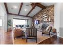 Inviting living room featuring exposed ceiling beams, stone fireplace, and seamless access to an outdoor patio with mountain views at 10640 Winding Pine Pt, Highlands Ranch, CO 80126