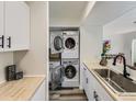 Efficient laundry area with stacked washer and dryer units and butcher block countertops at 12172 E Kepner Pl, Aurora, CO 80012