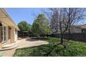 Spacious backyard featuring a concrete patio, grassy lawn, wooden fence, and mature trees at 12420 W Atlantic Ave, Lakewood, CO 80228