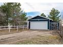 Detached garage features a large white door, side door, and a gravel driveway at 44626 Lariat Trl, Elizabeth, CO 80107