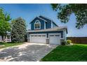 Two-story blue home featuring a three-car garage, manicured lawn, and mature trees at 901 Sage Sparrow Cir, Highlands Ranch, CO 80129