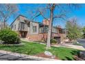 Beautiful home exterior with manicured lawn, mature trees, and brick and gray siding at 6969 W Yale Ave # 81, Denver, CO 80227