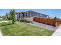 Well-maintained home exterior featuring lush green lawn and neutral stone accents, surrounded by wood fence at 17028 Osage St, Broomfield, CO 80023