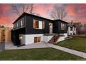 Charming home featuring a black exterior, white brick foundation, wood shutters, and a landscaped front yard at 4565 Elm Ct, Denver, CO 80211