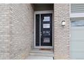 Stylish black front door with glass panels, complemented by light brick and a welcoming mat at 9130 Fraser River, Littleton, CO 80125