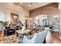 Inviting living room featuring a brick accent wall, hardwood floors, and comfortable seating at 6963 S Espana Way, Centennial, CO 80016