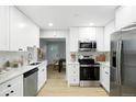 Bright kitchen with white cabinets, stainless appliances, and light wood flooring at 5541 E 65Th Ave, Commerce City, CO 80022