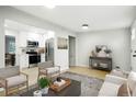 Bright living room with light hardwood floors, modern furniture, and an open-concept kitchen at 5541 E 65Th Ave, Commerce City, CO 80022
