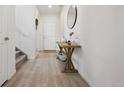 Inviting entryway with light wood floors, a decorative table with a mirror, and a view of the staircase at 131 S Vandriver Way, Aurora, CO 80018