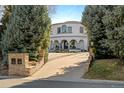 Elegant estate entrance with stone pillars, driveway, and mature trees at 3280 Cherryridge Rd, Cherry Hills Village, CO 80113