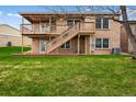 A backyard with a large green lawn, two-tiered deck and brick patio at 4927 Greenwich Way, Highlands Ranch, CO 80130