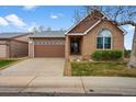 Charming single-Gathering brick home featuring a garage with decorative windows and a manicured lawn at 4927 Greenwich Way, Highlands Ranch, CO 80130